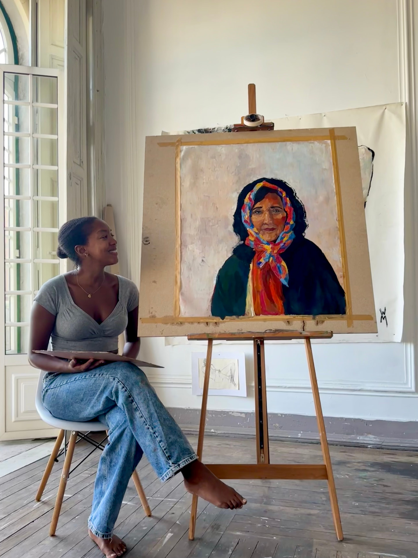 Zehma in her studio beside a portrait on the easel